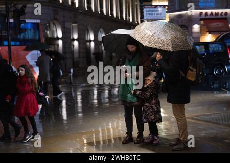 Touristen mit Regenschirmen an einer verregneten Winternacht in Aldwych, Londons Theaterviertel im West End, London, England, Großbritannien Stockfoto