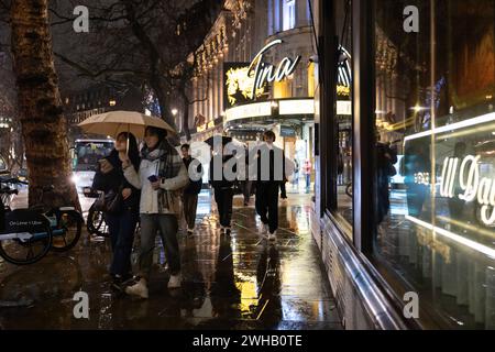 Touristen mit Regenschirmen an einer verregneten Winternacht in Aldwych, Londons Theaterviertel im West End, London, England, Großbritannien Stockfoto