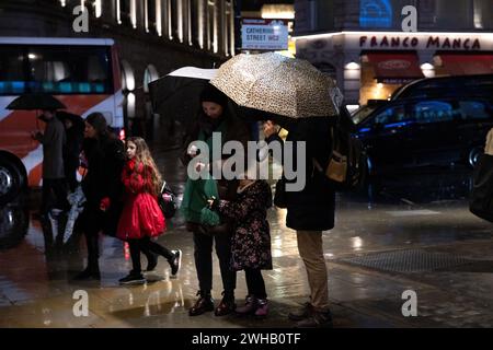 Touristen mit Regenschirmen an einer verregneten Winternacht in Aldwych, Londons Theaterviertel im West End, London, England, Großbritannien Stockfoto