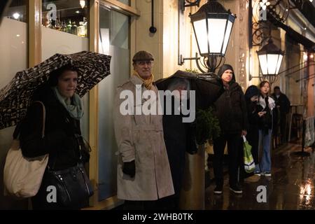 Touristen mit Regenschirmen an einer verregneten Winternacht in Aldwych, Londons Theaterviertel im West End, London, England, Großbritannien Stockfoto