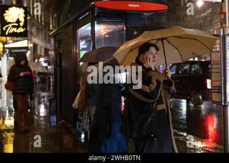 Touristen mit Regenschirmen an einer verregneten Winternacht in Aldwych, Londons Theaterviertel im West End, London, England, Großbritannien Stockfoto