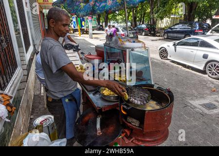 Ein Dominikaner, der in einem mobilen Küchenstand auf der Straße in Santo Domingo, Dominikanische Republik, Tosteine brät. Stockfoto