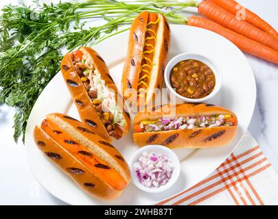 Karottenhunde mit Gewürzen und rohen Karotten auf Marmoroberfläche; pflanzliches Futterkonzept; Fleischalternative Stockfoto