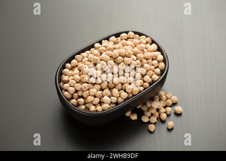 Kichererbsen in einer kleinen schwarzen Schüssel auf einem schwarzen Holztisch. Stockfoto