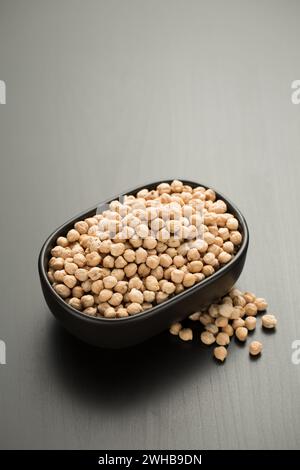 Kichererbsen in einer kleinen schwarzen Schüssel auf einem schwarzen Holztisch. Stockfoto