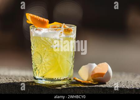 Ein Glas Whiskey-Sour-Cocktail, dekoriert mit Zitrone im Hintergrund der Bar. Stockfoto