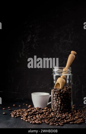 Kaffeebohnen in einem Glas. Geröstete Bohnen. Schwarzer Americano-Kaffee. Kaffeetasse mit Kaffeebohne Hintergrund. Coffee-Shop-Konzept, Kaffeeliebhaber und Co Stockfoto