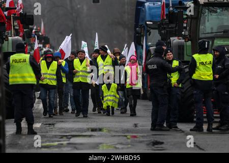 Posen, Polen, 9. Februar 2024. Bauern aus der Region Großpolen in Westpolen laufen mit polnischen Fahnen vor ihren Traktoren, während sie die Aleja Niepodleglosci Straße im Zentrum von Poznań blockieren, der Hauptstadt Großpolens während des bundesweiten Streiks der Bauern. Der Protest in Polen ist Teil des Protests der europäischen Landwirte gegen die EU-Verordnungen über den Grünen Deal. Die polnischen Landwirte fordern auch eine Änderung des EU-Abkommens mit der Ukraine über die Einfuhr landwirtschaftlicher Erzeugnisse in die EU. Der Protest in Poznań, der Hauptstadt von Großpolen, wurde von Rola Wielkopolska und organisiert Stockfoto