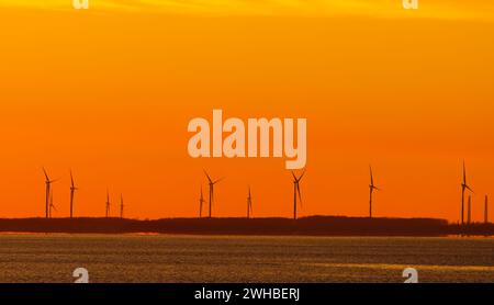 Windturbinen unter einem orangen Himmel Sonnenuntergang im Winter auf Amherst Island, Ontario, Kanada Stockfoto