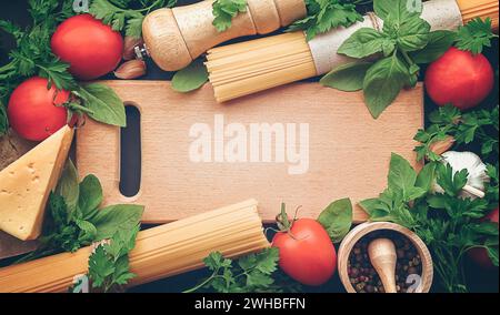 Zutaten zum Kochen von Pasta Spaghetti alla puttanesca - italienisches Nudelgericht mit Tomaten, schwarzen Oliven, Kapern, Sardellen und Petersilie. Draufsicht, FLA Stockfoto