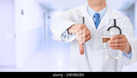 Nahaufnahme eines Arztes Hände, die im Krankenhaus ein Wasserglas mit den Daumen nach unten halten Stockfoto