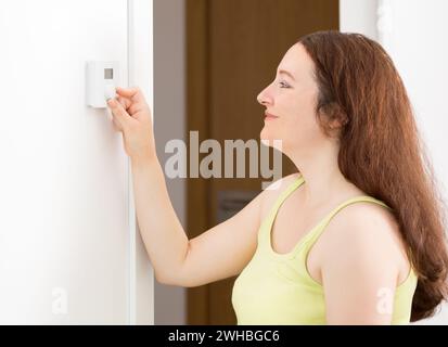 Aufnahme eines Seitenporträts eines schönen digitalen Thermostats mit Druckknopf für glückliche Frau zu Hause Stockfoto