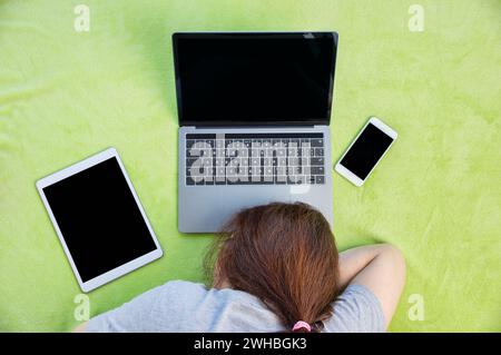 Überarbeitete und müde Geschäftsfrau, die bei der Arbeit zu Hause über einem Laptop schläft Stockfoto