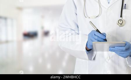 Zugeschnittenes Bild eines jungen Arztes, der auf seinem Touchpad im Krankenhaus und im Kopierraum tippt Stockfoto