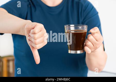 Vorderansicht Nahaufnahme einer Frau, die zu Hause eine Kaffeetasse mit dem Daumen nach unten hält Stockfoto