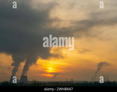 Industrielandschaft in Russland. Der Rauch aus der Kraft-Wärme-Kopplung steigt bei Sonnenuntergang sehr hoch an einem orangefarbenen Abendhimmel auf Stockfoto