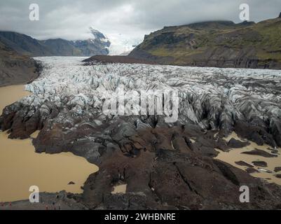 Svinafellsjokull-Gletscher in Island an einem bewölkten Tag, einzigartige Eisformationen umgeben von Bergen und eine Gletscherlagune aus der Vogelperspektive. Natur und Stockfoto