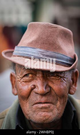 Ein Porträt eines älteren Ladakhi-Mannes, der einen verblassten braunen Hut trägt. Stockfoto