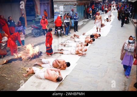 Bhaktapur, Nepal. Februar 2024. Hinduistische Gläubige beten, indem sie während eines einmonatigen Swasthani Brata Katha Festivals in Bhaktapur auf dem Boden krabbeln. Das monatelange Festival, das Gott Madhavnarayan und Göttin Swasthani gewidmet ist, beinhaltet die Rezitation von Volksgeschichten über wundersame Meisterleistungen, die von ihnen in vielen Hinduhaushalten durchgeführt werden. Quelle: SOPA Images Limited/Alamy Live News Stockfoto