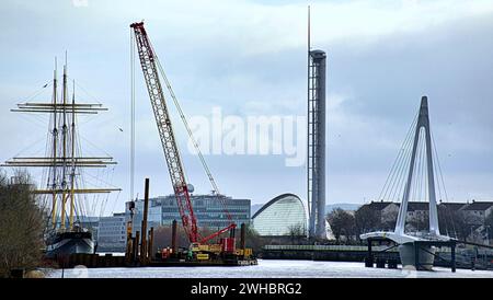 Glasgow, Schottland, Großbritannien. Februar 2024. Das Projekt der Govan-Partick Bridge umfasst den Bau einer neuen Fußgänger-/Radbrücke über den Fluss Clyde Cloudy und die Tanzwelle, das längste Wandgemälde der Stadt, feiert das Erbe des Flusses clyde und verläuft entlang des Ufers und veranschaulicht die Orte und die Geschichte der neuen Brücke nach govan wird neben dem Museum und dem Clipper-Schiff Glenlee gebaut, während das neueste Kriegsschiff der Marine hms glasgow auf der anderen Bank von Bae-Systemen gebaut wird. Credit Gerard Ferry/Alamy Live News Stockfoto