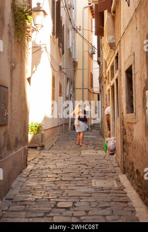 Piran, Slowenien - 26. August 2023: Mutter mit einem Kind in den Armen entlang der Gassen von Pirano Stockfoto