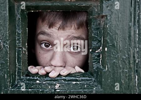 Das Gesicht des Gefangenen schaut durch das Gefängnisfenster Stockfoto