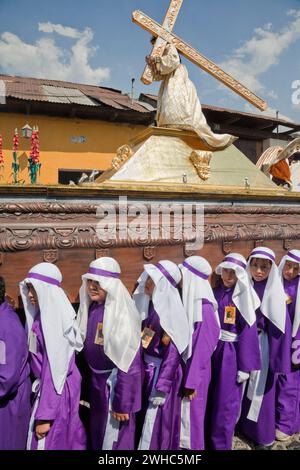 Antigua, Guatemala. Jugendliche Jungen, die während der Karwoche einen Schwimmer in einer religiösen Prozession tragen, La Semana Santa. Stockfoto