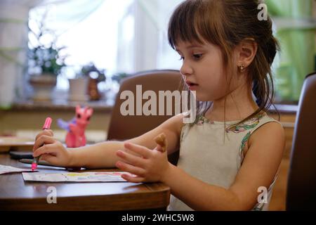 Ein kleines Mädchen, das einen Filzstift zeichnet. Das Kind engagiert sich zu Hause für Kreativität. Stockfoto