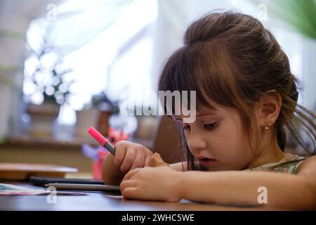 Ein kleines Mädchen, das einen Filzstift zeichnet. Das Kind engagiert sich zu Hause für Kreativität. Stockfoto