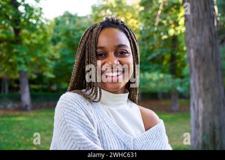 Porträt einer jungen, schönen afroamerikanischen Frau mit Zöpfen, die lächelnd in die Kamera blickt. Stockfoto