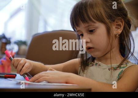 Ein kleines Mädchen, das einen Filzstift zeichnet. Das Kind engagiert sich zu Hause für Kreativität. Stockfoto