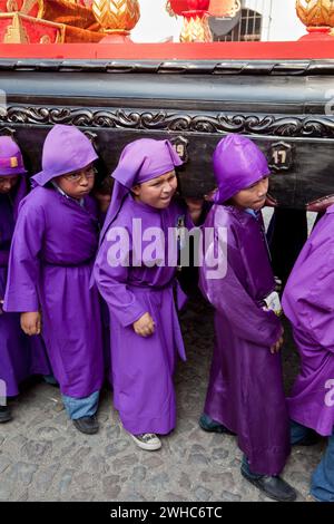 Antigua, Guatemala. Jugendliche Jungen, die während der Karwoche einen Schwimmer in einer religiösen Prozession tragen, La Semana Santa. Stockfoto