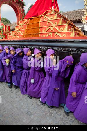 Antigua, Guatemala. Jugendliche Jungen, die während der Karwoche einen Schwimmer in einer religiösen Prozession tragen, La Semana Santa. Stockfoto