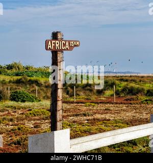 Wegweiser, Entfernung nach Afrika 15 km, Kitesurfer am Horizont, Tarifa, Cadiz, Andalusien, Spanien Stockfoto