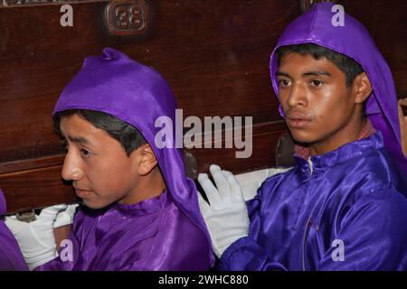 Antigua, Guatemala. Zwei junge Männer, Cucuruchos, mit einem Schwimmer (Anda) in einer religiösen Prozession während der Karwoche, La Semana Santa. Stockfoto