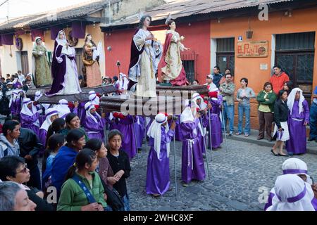 Antigua, Guatemala. Cucuruchos mit religiösen Figuren in einer Prozession während der Karwoche, La Semana Santa. Stockfoto