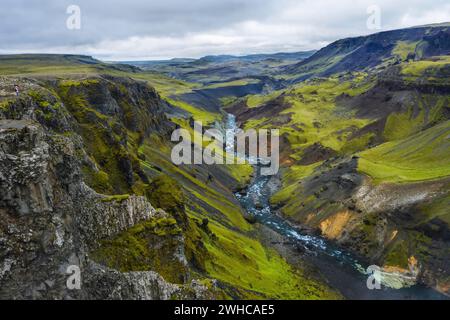 Frau Wanderer genießen die Highlands von Island. Fluss Fossa Strom im Landmannalaugar Canyon Tal. Hügel und Klippen sind von grünem Moos bedeckt. Stockfoto