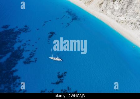 Lefkada, Griechenland. Abgelegener weißer Egremni-Strand mit einsamem Luxus-Yacht-Boot an der türkisfarbenen Bucht am Ionischen Meer. Stockfoto