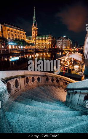 Die Alsterfleet und das Rathaus in Hamburg bei Nacht. Wunderschön beleuchtete Innenstadt, Stadtzentrum. Stockfoto