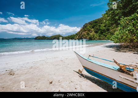 Traditionelles banca-boot vor dem abgelegenen tropischen Strand mit exotischer blauer Lagune. El Nido, Philippinen. Stockfoto