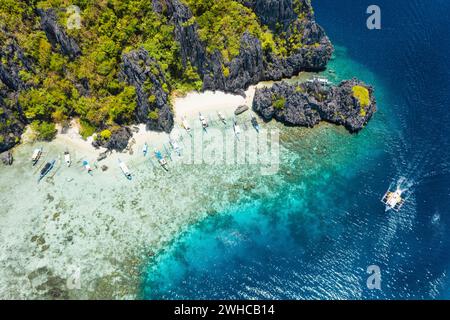 Touristenboote aus der Vogelperspektive, die auf der tropischen Insel Shimizu vor Anker liegen. Kalkstein Küstenfelsen, weißer Sandstrand in blauem Wasser. El Nido, Palawan, Philippinen. Stockfoto