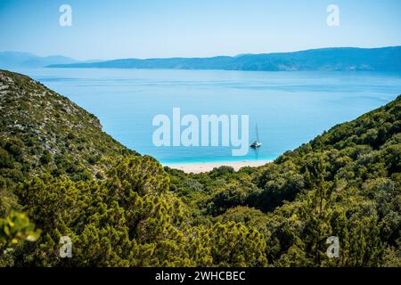 Wanderweg zum weißen Sandstrand, der in der Ferne erscheint, umgeben von mediterraner Vegetation. Fantastische Meereslandschaft Griechenland Ionische Inseln. Sommerabenteuerurlaub. Stockfoto