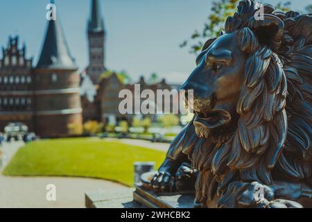 Bronzene Löwenstatue vor dem Holstentor – Holstentor, ein Stadttor, das die westliche Grenze der Altstadt Lübecks in Schleswig-Holstein markiert. Stockfoto