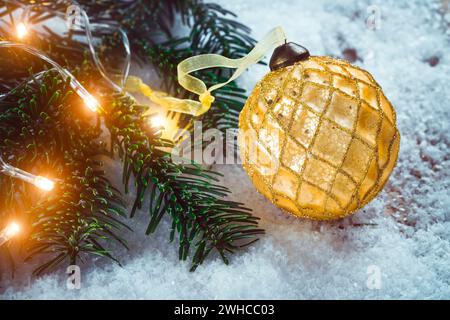 Golden Christmas Ball auf Schnee in der Nähe von Zweige der Tanne. Festliche Hintergrund mit kopieren. Stockfoto