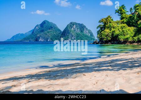 Sandstrand mit Palmen Schatten, riesige Felsen im Hintergrund, El Nido, Palawan, Philippinen. Stockfoto