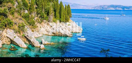 Felsenküste von Zypressen bedeckt und tourest Boote im azurblauen Wasser, in der Nähe von Kalami, Corfu. Banner Stockfoto