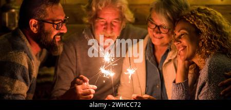 Gruppe von Menschen feiert das neue Jahr 2021 nach einem harten 2020 - Bye 2020 Konzept - Familie genießen und Spaß haben zusammen mit Wunderkerzen zu Hause essen Pizza beim Abendessen - christidas Konzept Stockfoto