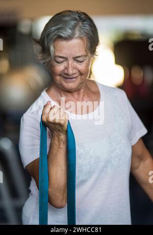 Reife Frau allein in der Turnhalle tun Übungen mit einem Elastisch - gesund und Fitness Lifestyle und Konzept - Senior Oder Rentner arbeiten sie gesund Stockfoto