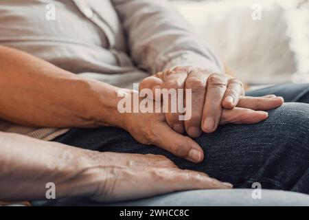 Nahaufnahme älterer, liebevoller Frau, die faltige Hände des reiferen Ehemanns bedeckt und zu Hause Liebe und Unterstützung zeigt. Fürsorgliche Familienpaare mittleren Alters, die aufrichtige, vertrauensvolle und ehrliche Gespräche genießen. Stockfoto