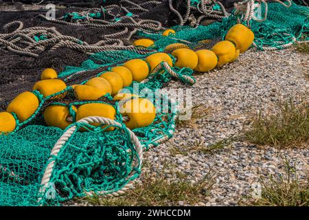 Nahaufnahme großer schwarzer und grüner Fischernetze mit gelben Schwimmern, die in Südkorea zum Trocknen auf dem Boden liegen Stockfoto